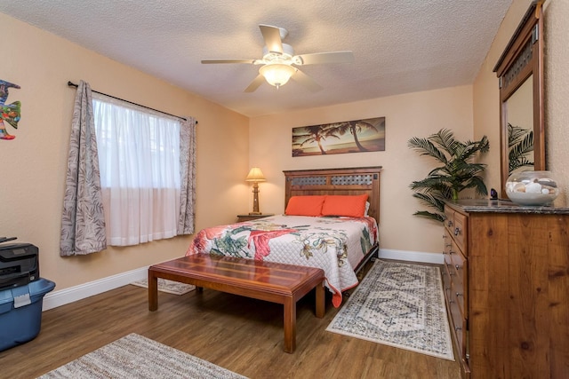 bedroom featuring baseboards, a textured ceiling, wood finished floors, and a ceiling fan