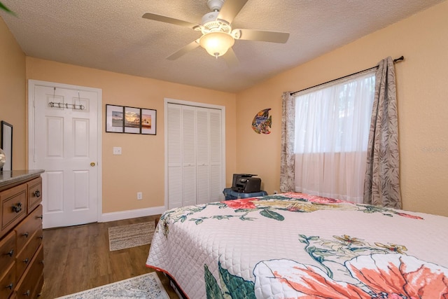 bedroom featuring dark wood-type flooring, a textured ceiling, a closet, baseboards, and ceiling fan