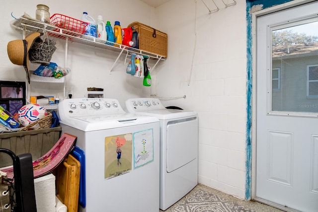 laundry area with concrete block wall, independent washer and dryer, and laundry area