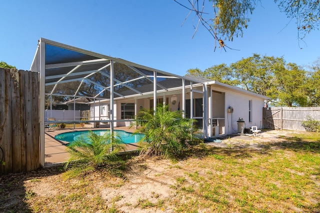 back of house with a fenced in pool, a lanai, stucco siding, a fenced backyard, and a patio area