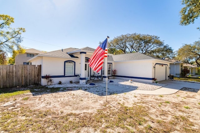 view of front of house with fence, driveway, a shingled roof, stucco siding, and a garage