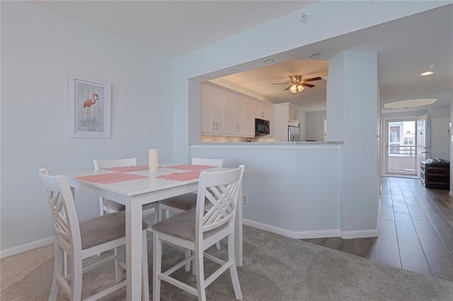 carpeted dining space with baseboards and a ceiling fan