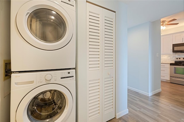 washroom with light wood finished floors, baseboards, laundry area, stacked washing maching and dryer, and a ceiling fan