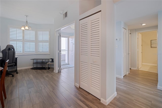 hallway featuring wood finished floors, visible vents, and baseboards