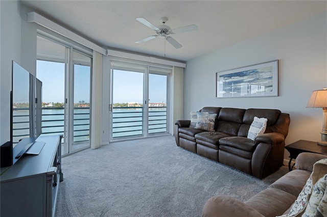 living room with a water view, carpet floors, and ceiling fan