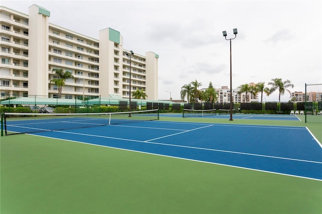 view of tennis court with community basketball court and fence