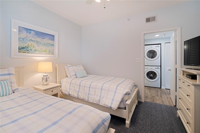 bedroom with stacked washer / drying machine, a ceiling fan, carpet, and baseboards