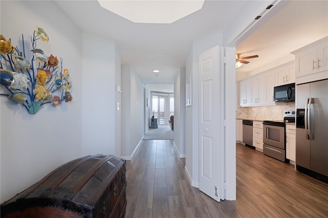 corridor with dark wood finished floors, recessed lighting, and baseboards