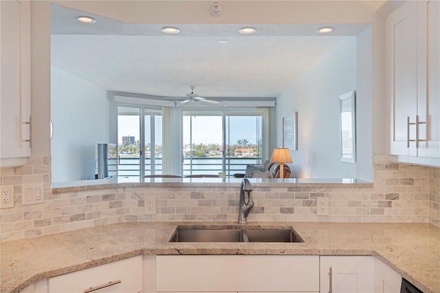 kitchen with a sink, a water view, tasteful backsplash, a ceiling fan, and recessed lighting