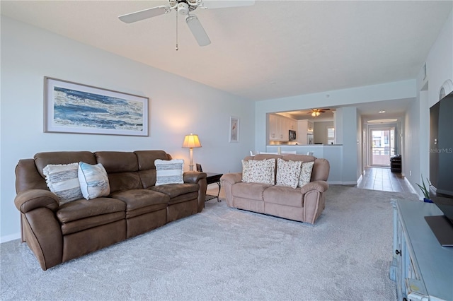 living room with ceiling fan, light carpet, and baseboards