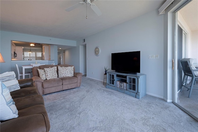 carpeted living room with ceiling fan and baseboards