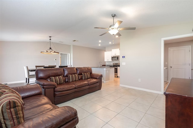 living room with lofted ceiling, light tile patterned floors, baseboards, and ceiling fan