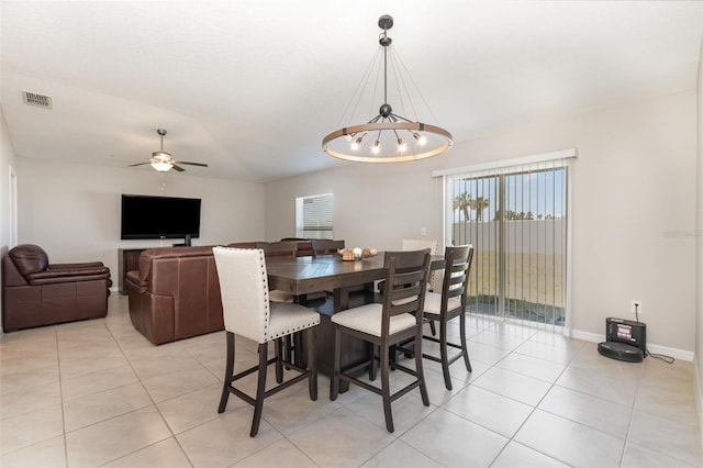 dining area with light tile patterned flooring, visible vents, ceiling fan with notable chandelier, and baseboards