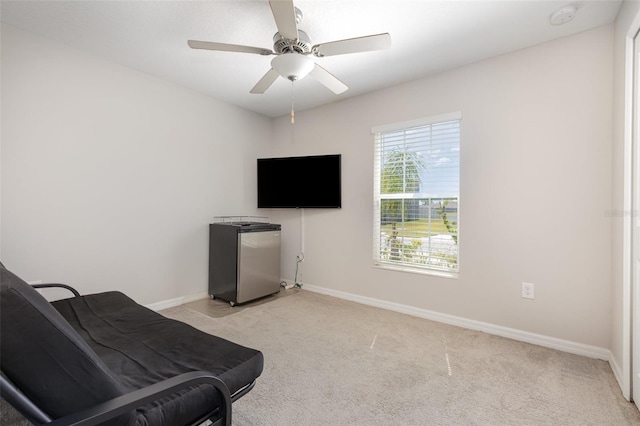 sitting room featuring baseboards, light carpet, and ceiling fan