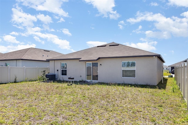 rear view of property with stucco siding, cooling unit, a lawn, and fence