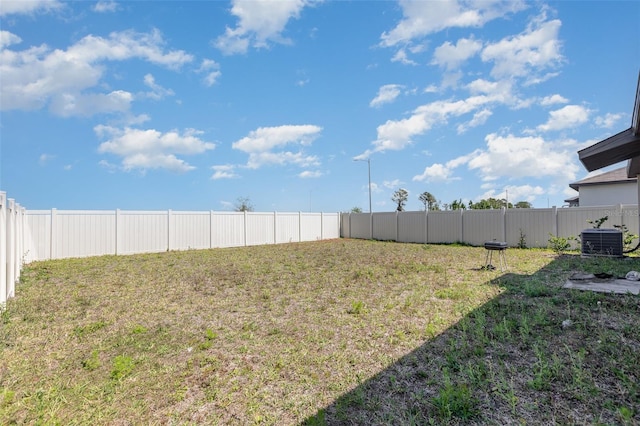 view of yard with a fenced backyard and central AC