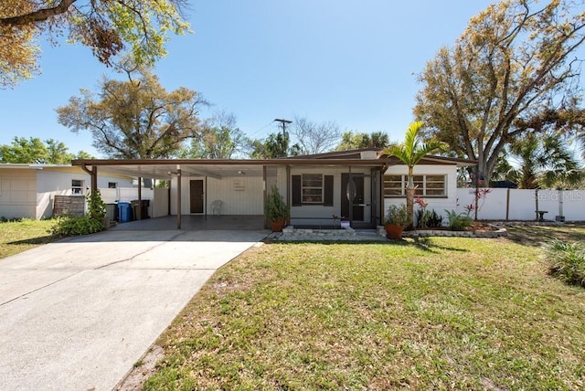 ranch-style house featuring an attached carport, concrete driveway, fence, and a front lawn