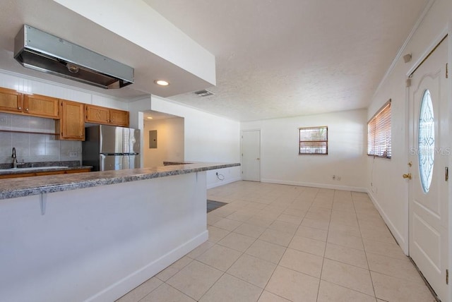 kitchen with tasteful backsplash, a textured ceiling, freestanding refrigerator, light tile patterned floors, and baseboards