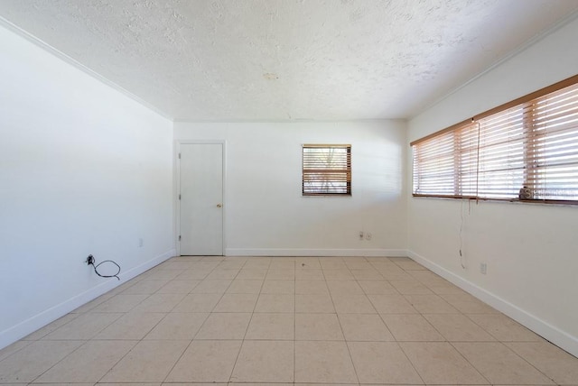 spare room featuring light tile patterned floors, baseboards, and a textured ceiling