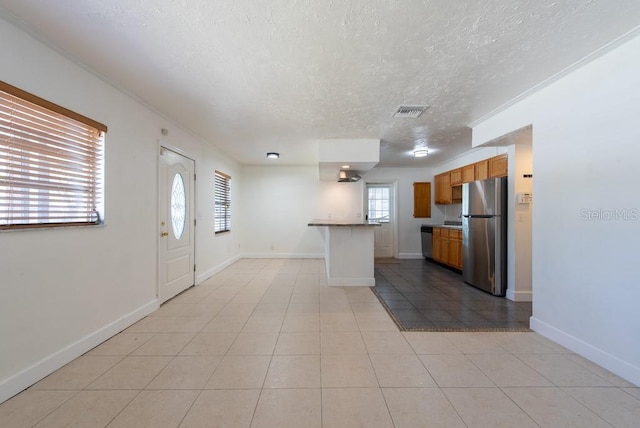 kitchen with brown cabinetry, baseboards, visible vents, stainless steel appliances, and a textured ceiling