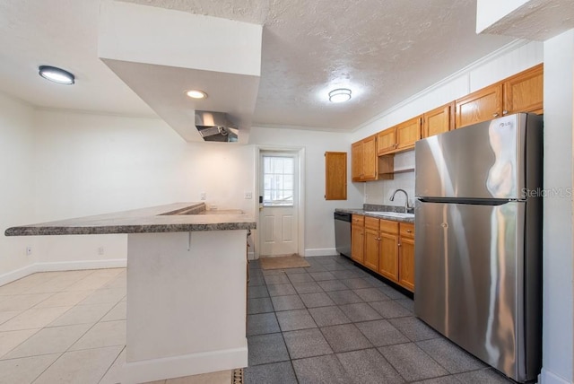 kitchen with baseboards, a peninsula, a textured ceiling, stainless steel appliances, and a sink