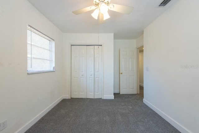 unfurnished bedroom with baseboards, visible vents, ceiling fan, a closet, and dark colored carpet