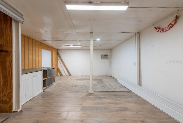 finished basement with light wood finished floors and a wall mounted AC