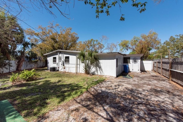 back of property with a yard, central air condition unit, and a fenced backyard