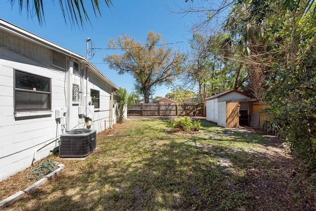 view of yard featuring a storage unit, cooling unit, an outbuilding, and a fenced backyard