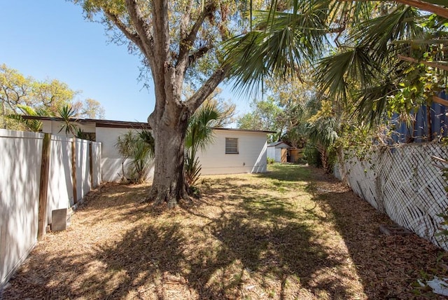 view of yard featuring an outbuilding, a fenced backyard, and a storage shed