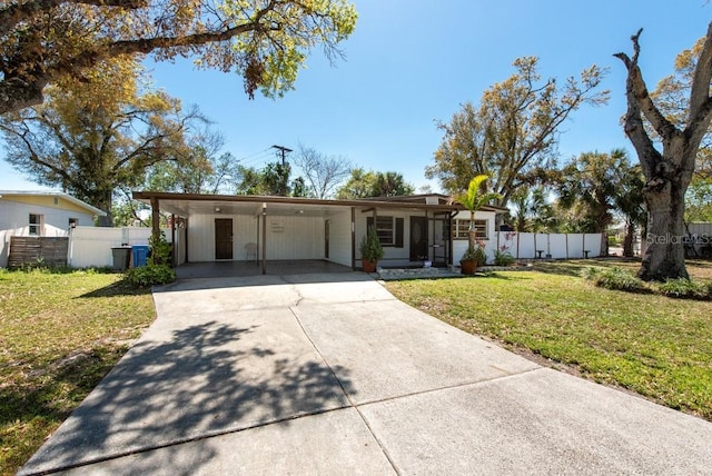 view of front facade with driveway, a carport, a front lawn, and fence