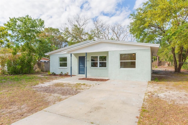 view of front of home with stucco siding, concrete driveway, and fence