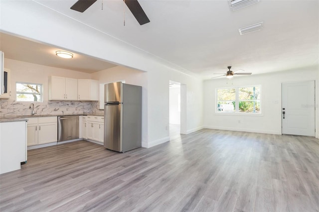 kitchen with a ceiling fan, a sink, backsplash, open floor plan, and stainless steel appliances