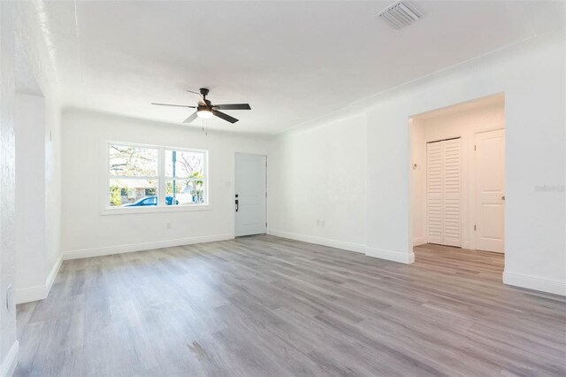 unfurnished living room featuring visible vents, baseboards, a ceiling fan, and wood finished floors