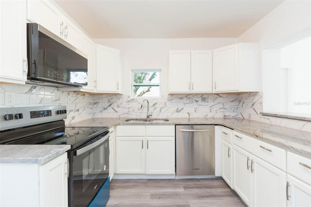 kitchen with a sink, stainless steel appliances, white cabinets, decorative backsplash, and light stone countertops