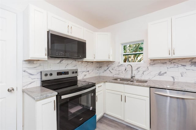 kitchen with light stone countertops, tasteful backsplash, appliances with stainless steel finishes, and a sink