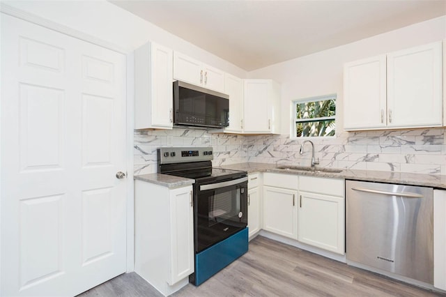 kitchen with light stone counters, decorative backsplash, stainless steel appliances, white cabinetry, and a sink