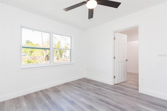 spare room featuring baseboards, wood finished floors, and a ceiling fan