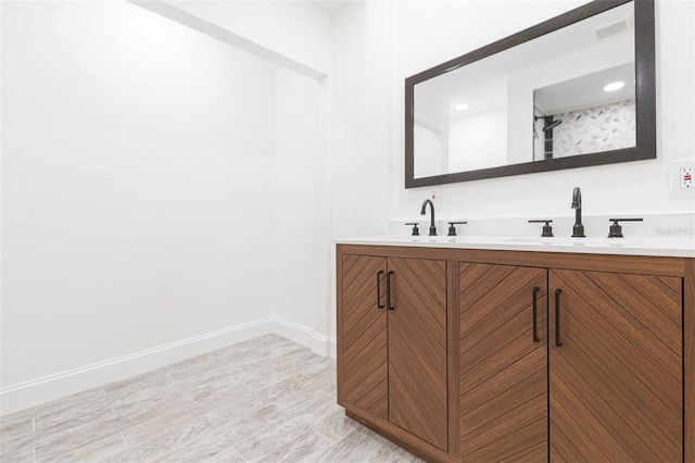 bathroom featuring double vanity, visible vents, baseboards, and a sink