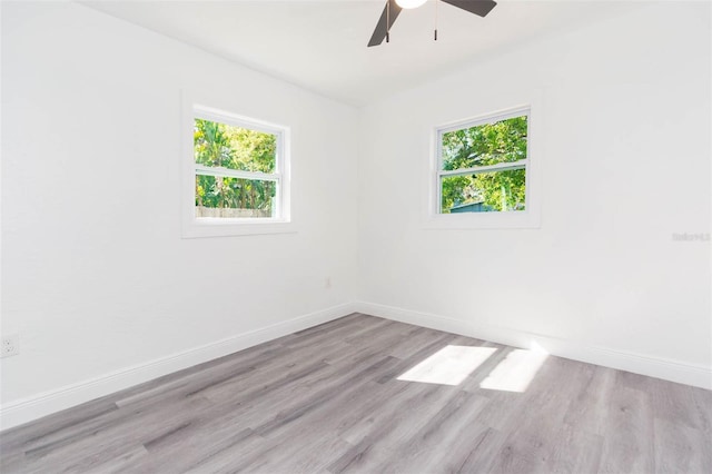 unfurnished room featuring wood finished floors, baseboards, and a wealth of natural light