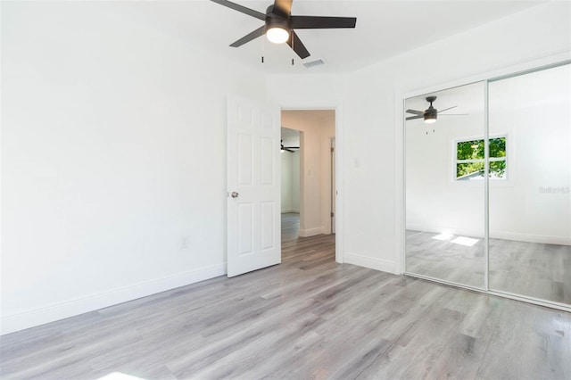 unfurnished bedroom featuring visible vents, wood finished floors, a closet, baseboards, and ceiling fan