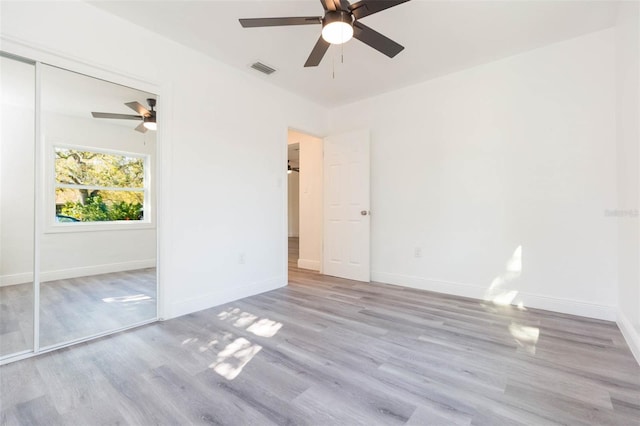 unfurnished bedroom featuring a closet, visible vents, baseboards, and wood finished floors