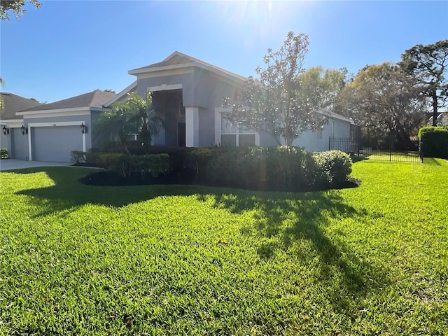 view of front of property with stucco siding, a front lawn, an attached garage, and fence