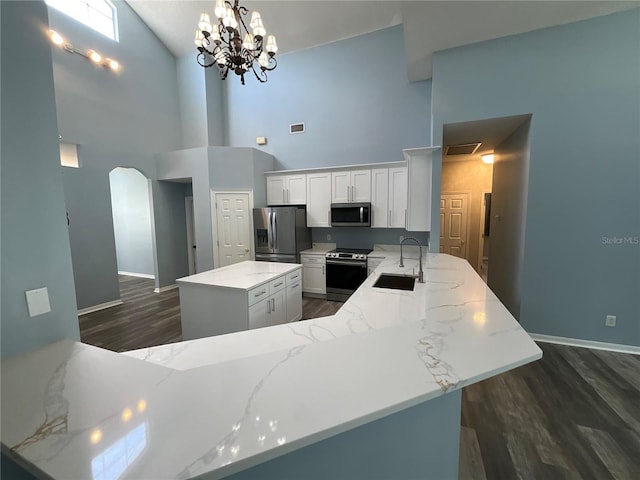 kitchen with visible vents, arched walkways, a sink, stainless steel appliances, and white cabinetry