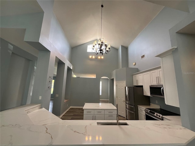 kitchen with visible vents, a kitchen island, a chandelier, arched walkways, and stainless steel appliances