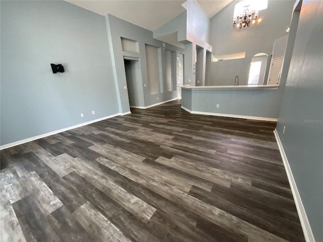 unfurnished living room featuring dark wood finished floors, an inviting chandelier, and baseboards