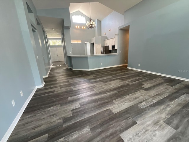 interior space featuring dark wood-style floors, baseboards, high vaulted ceiling, and an inviting chandelier