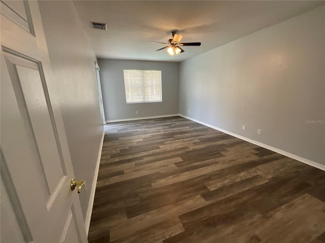 spare room with visible vents, baseboards, dark wood finished floors, and a ceiling fan