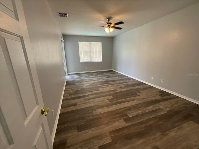 spare room featuring baseboards, a ceiling fan, and dark wood-style flooring