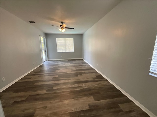 spare room with dark wood-style floors, visible vents, baseboards, and a ceiling fan